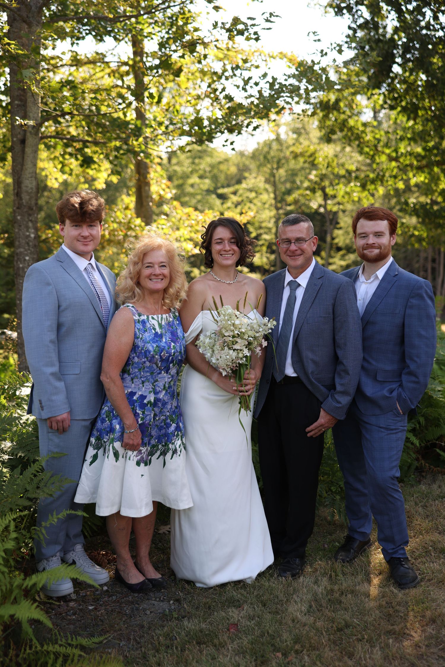 Wedding family portrait with bride groom and three family members in outdoor garden setting.
