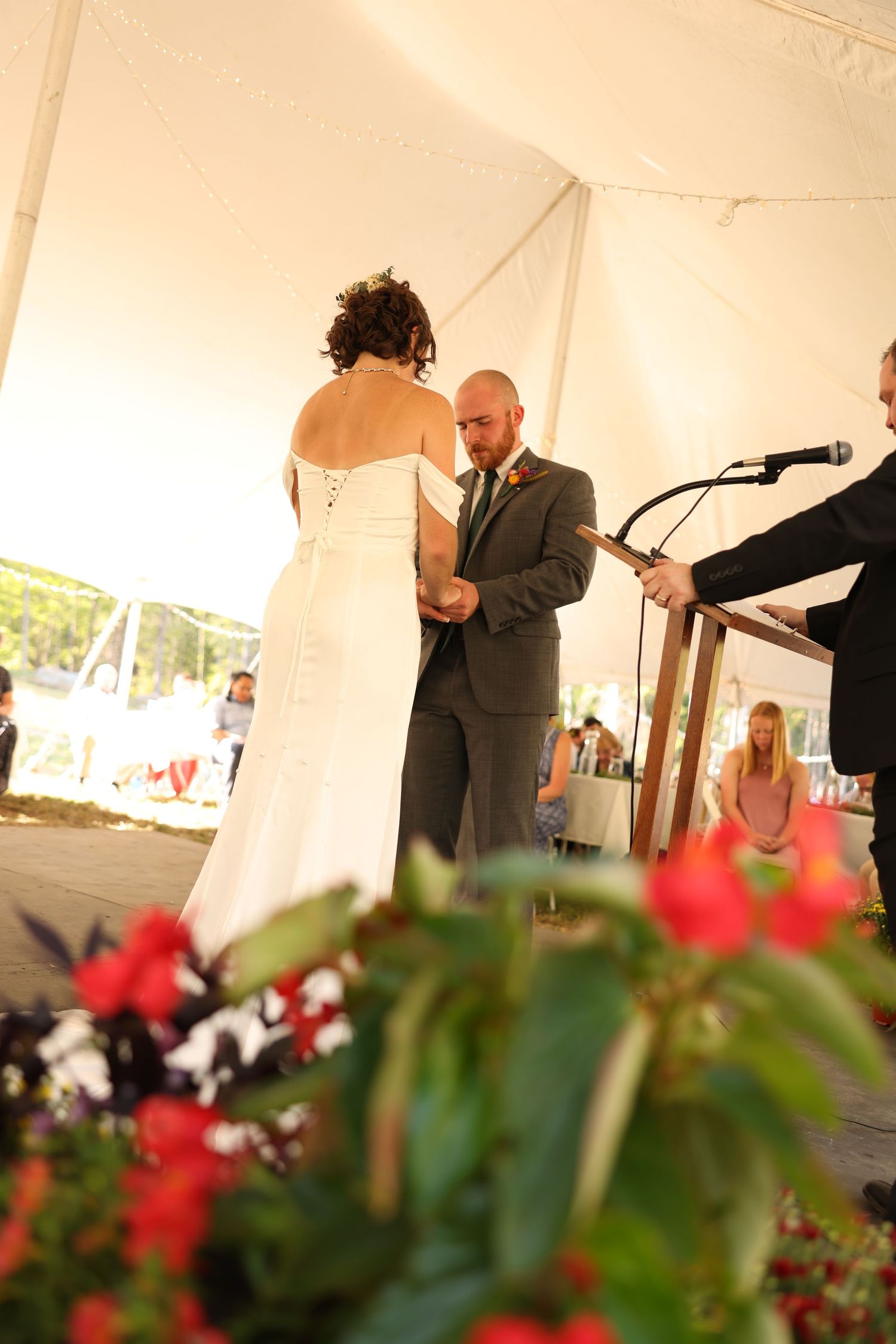 Bride and groom exchanging vows under white tent during outdoor wedding ceremony.