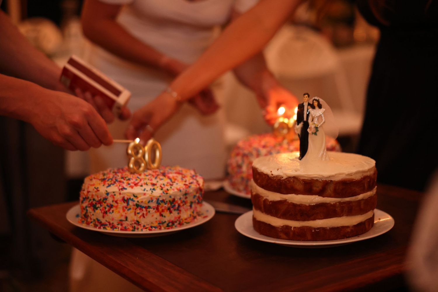 Two celebration cakes including a wedding cake with bride and groom topper and a sprinkle cake.