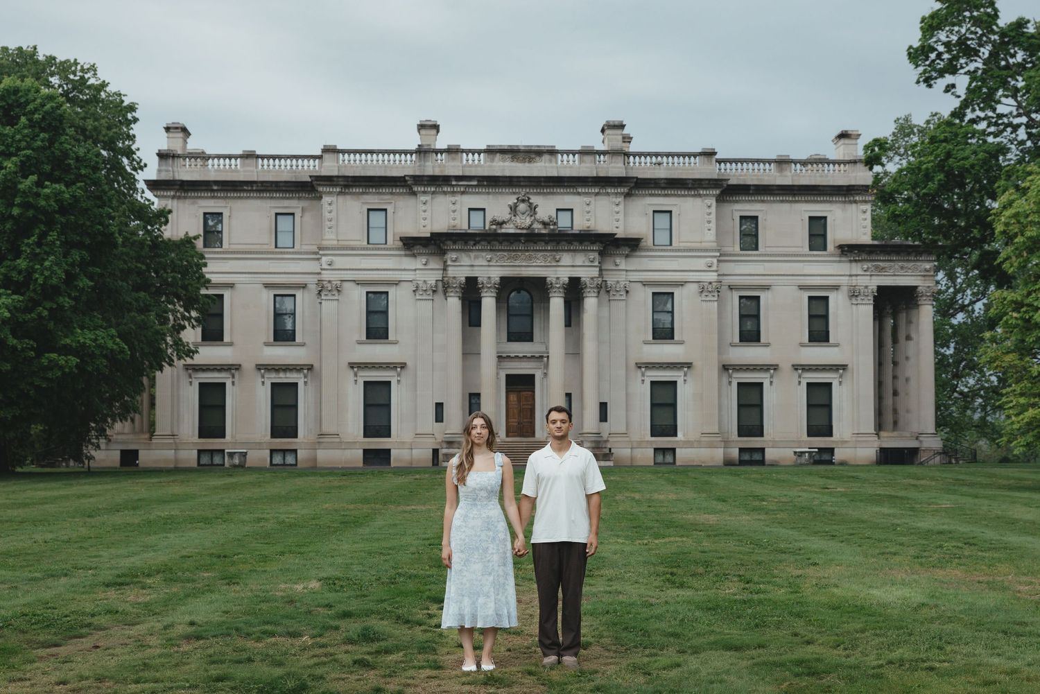 Couple poses in front of a grand neoclassical building with columns during their wedding day outdoor portrait session.