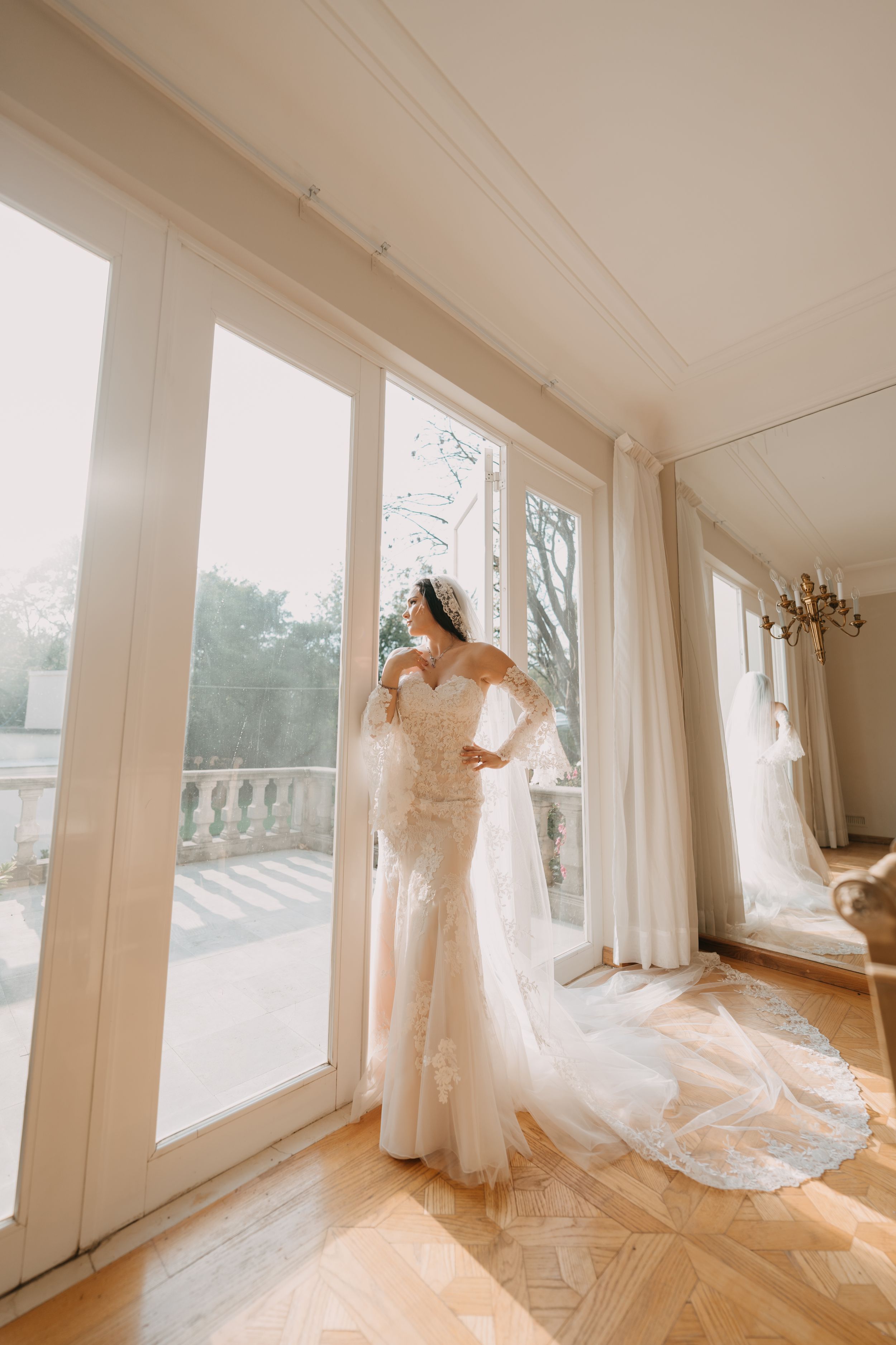 Sunlit bridal boutique interior with multiple wedding dresses on display near large windows.