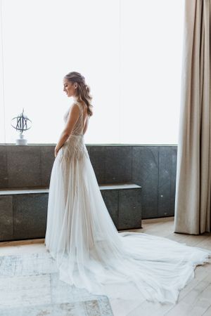A flowing white wedding dress with a long cathedral veil photographed in a bright modern room.