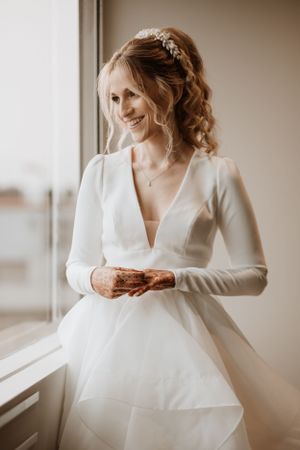 Elegant white wedding dress with long sleeves photographed near a bright window.