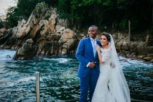 Coastal wedding portraits with dramatic ocean cliffs and blue waters in background.