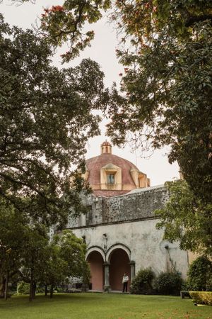 Historic Spanish mission church with white walls and arched entrance framed by trees.