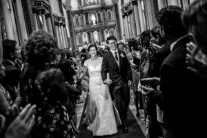 Wedding guests celebrate in historic church corridor with joyful expressions.