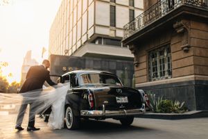Classic vintage car parked outside a building at sunset with golden light streaming through.