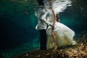 Underwater wedding photography session with flowing white dress in crystal clear blue water.