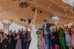 Wedding celebration with guests throwing confetti in an indoor venue.