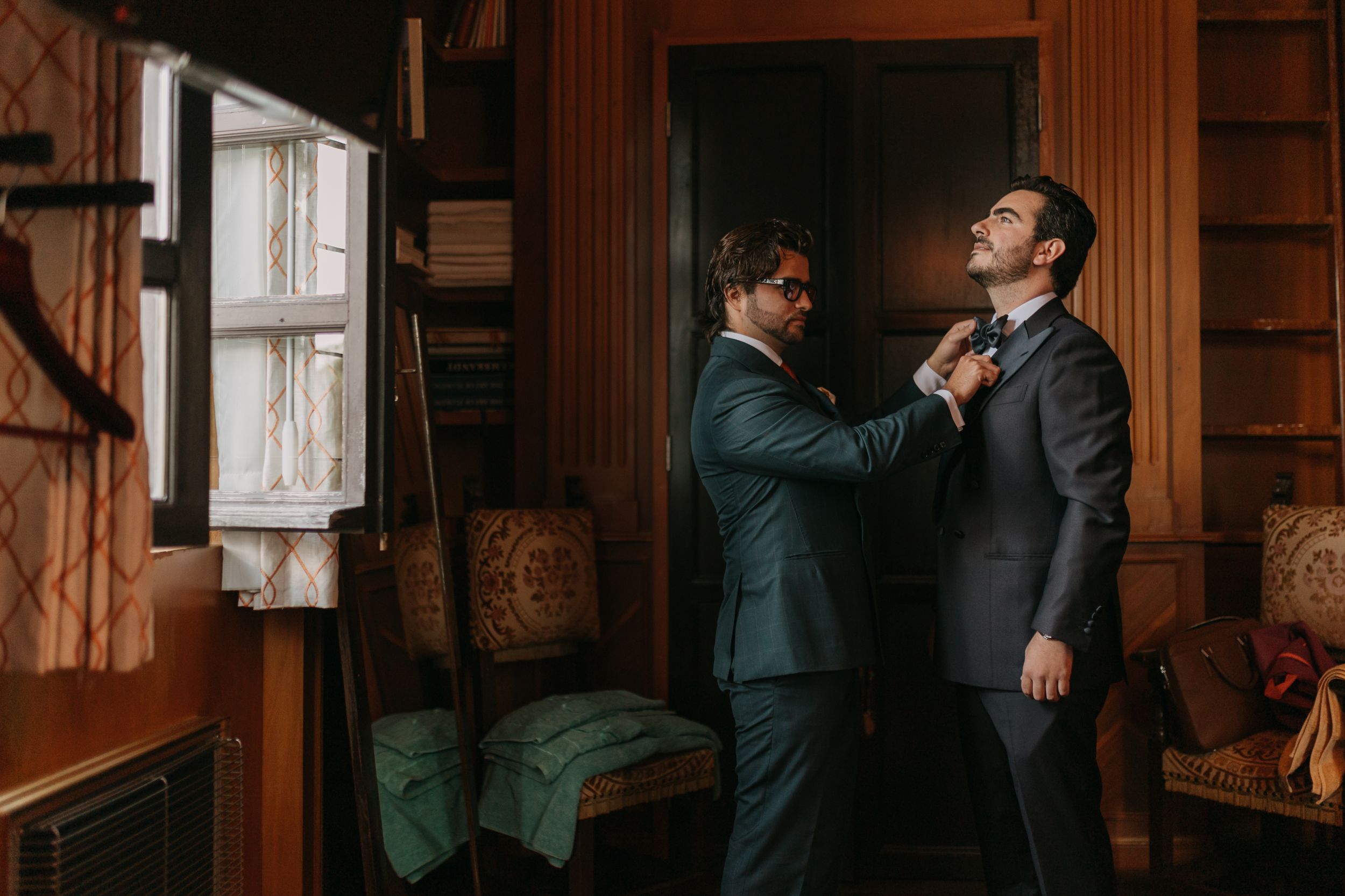 Wedding party members in formal attire gather in a dimly lit room.