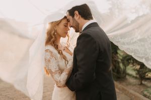 Elegant couple embracing during their wedding photoshoot with flowing veil.