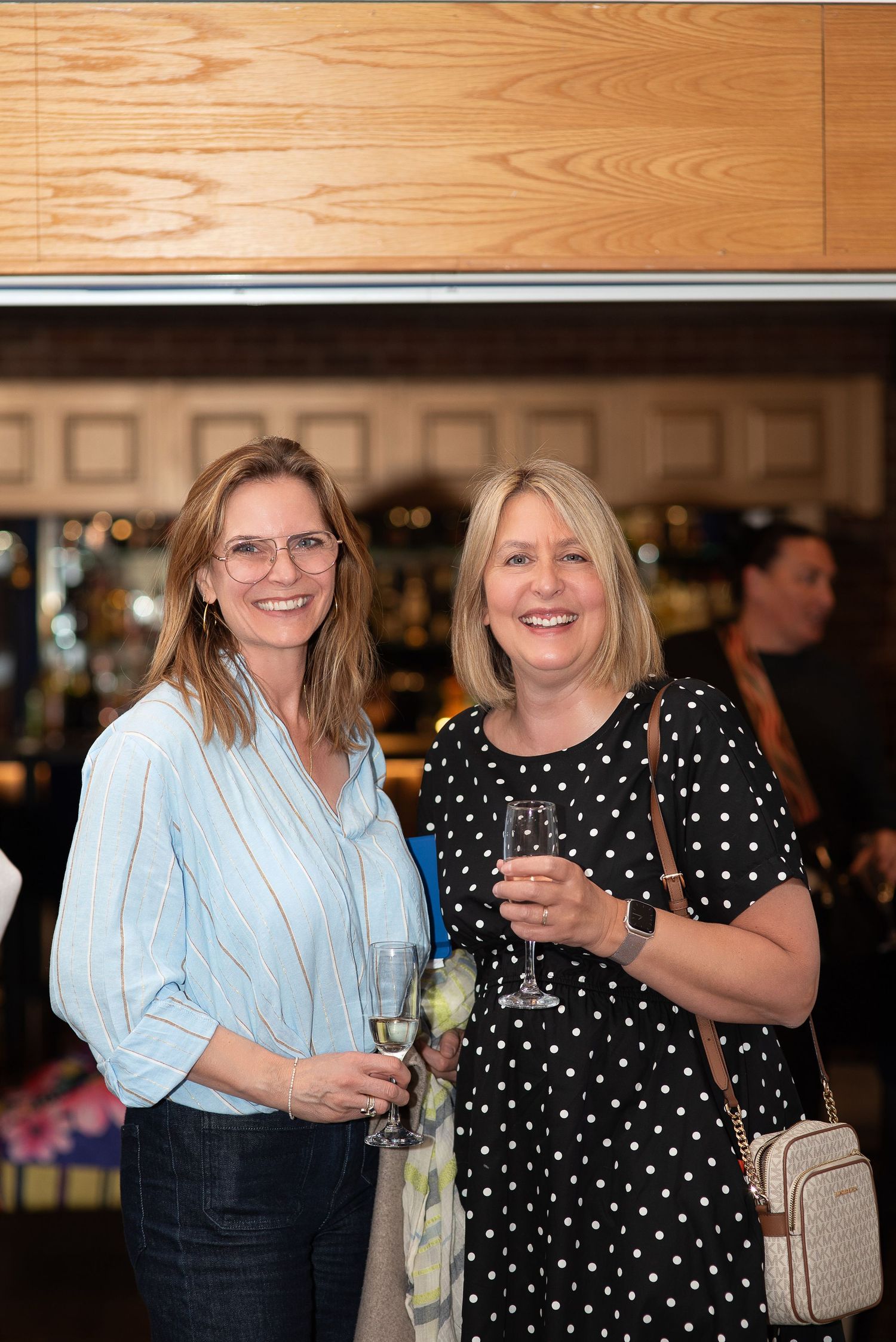 Women networking at a professional luncheon event with a presentation screen visible in the background.