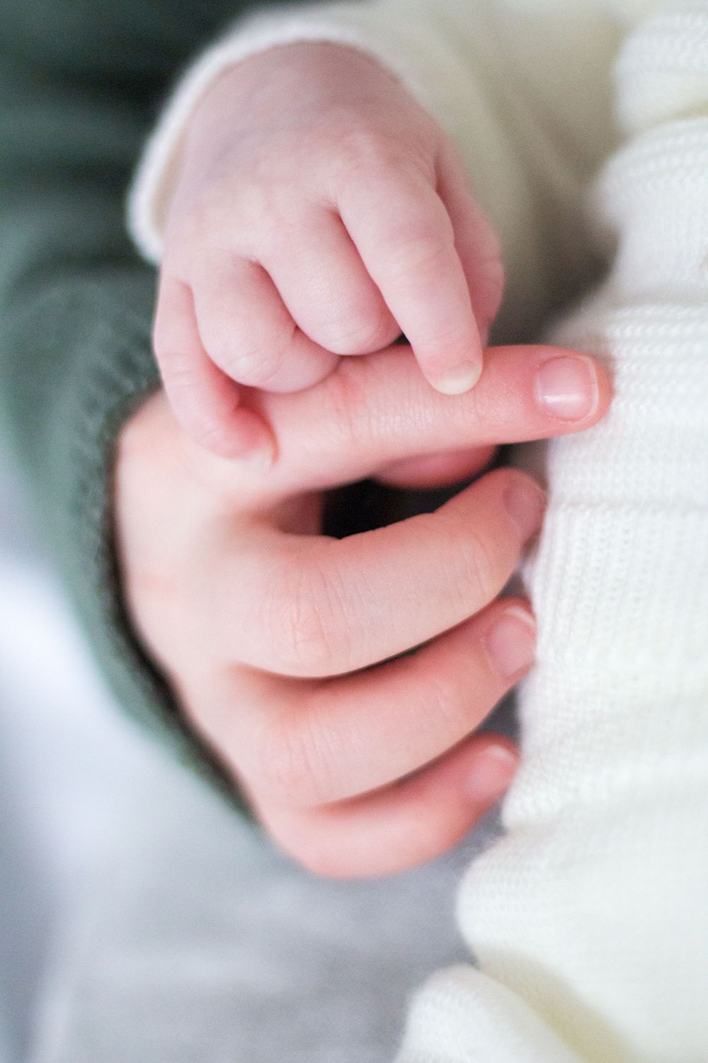 Close-up of a newborn baby's tiny hand gently gripping an adult's finger.