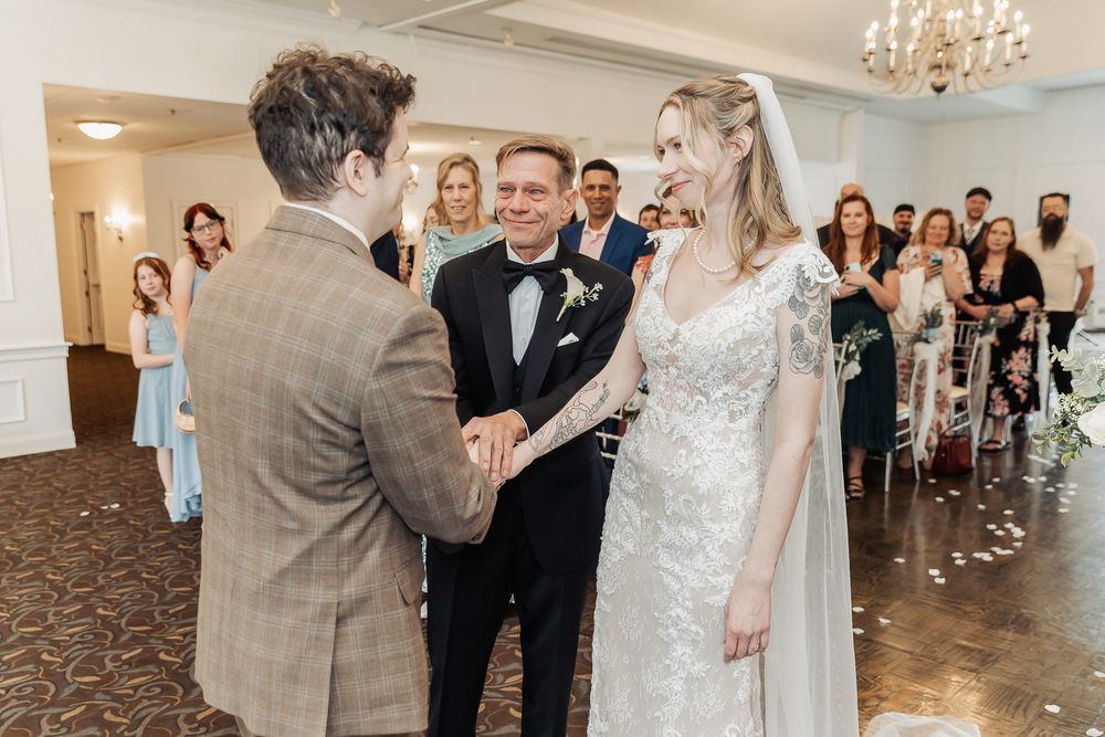 Bride and groom exchange vows at elegant wedding ceremony with guests watching in decorated venue.