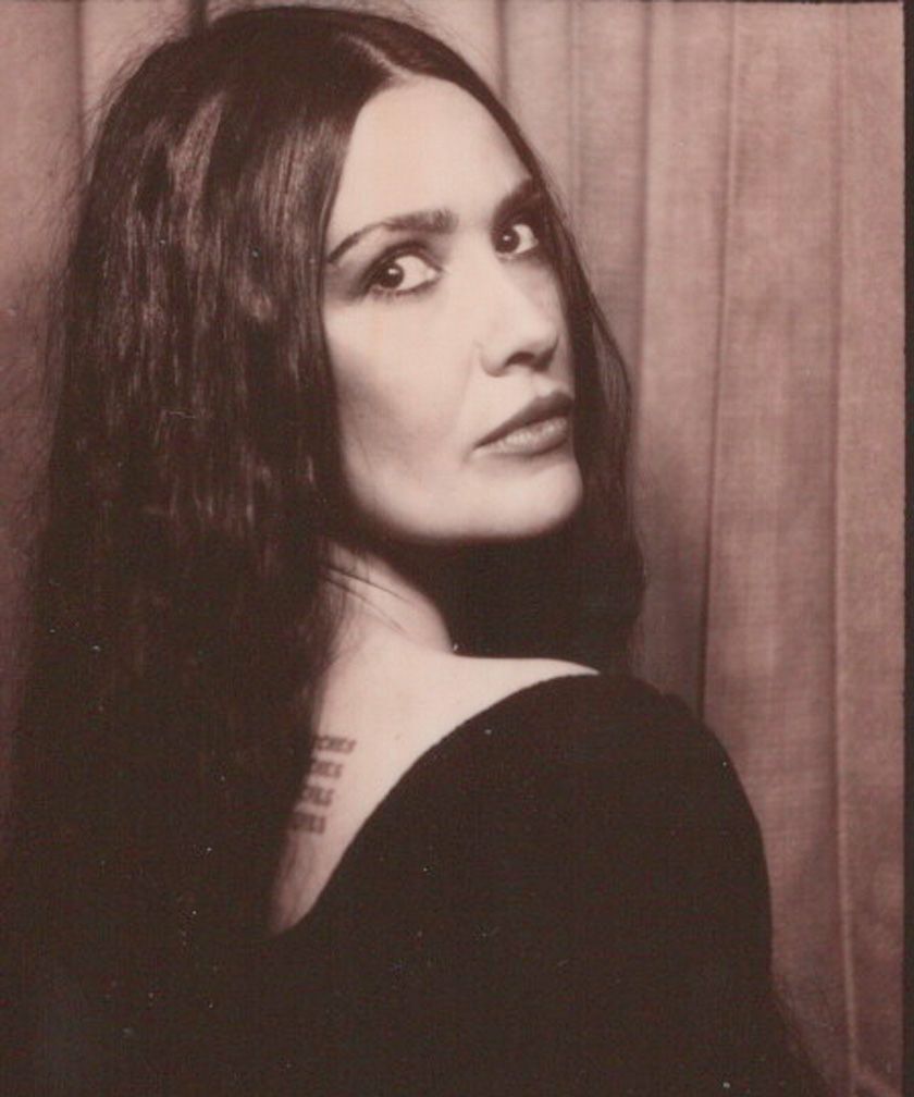 Self portrait of content creator in vintage photo booth. Model is looking back at the camera with her dark eyes and hair.