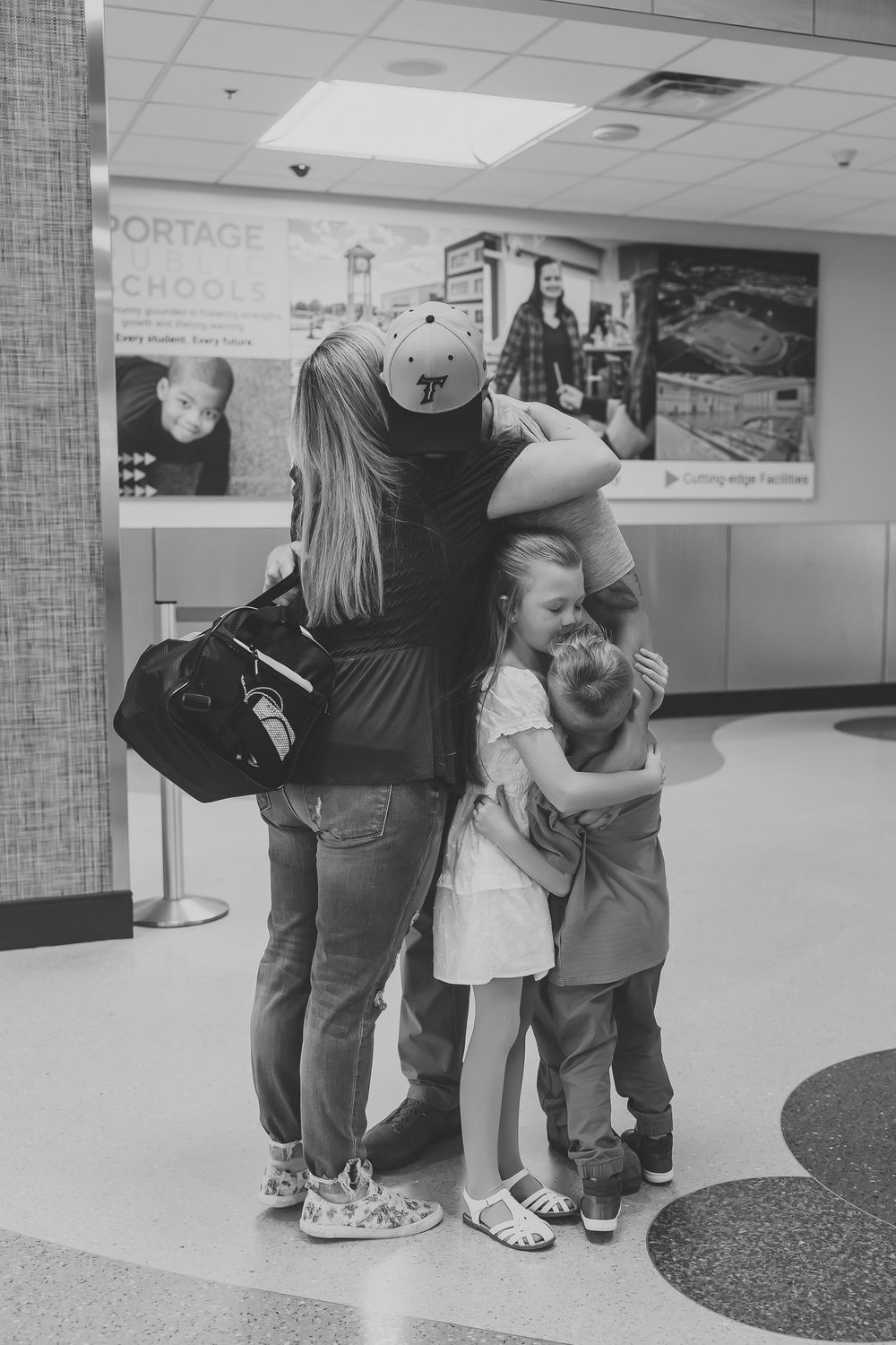 Emotional family group hug in school hallway, black and white photography.