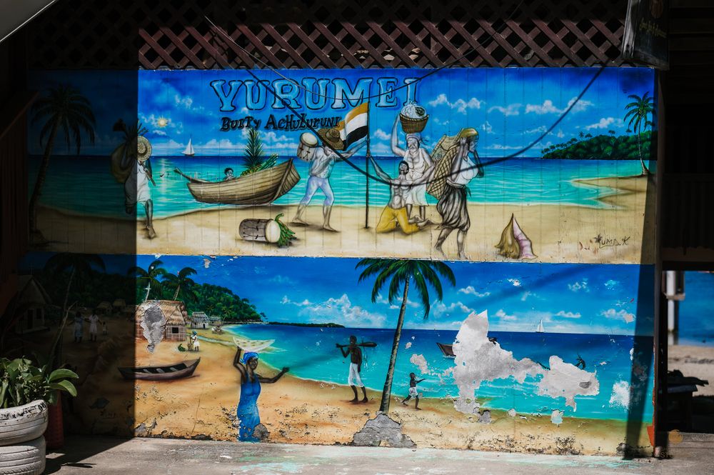 Colorful Yurumi Bar & Restaurant mural painting depicting traditional African coastal fishing village scene with boats and palm trees.