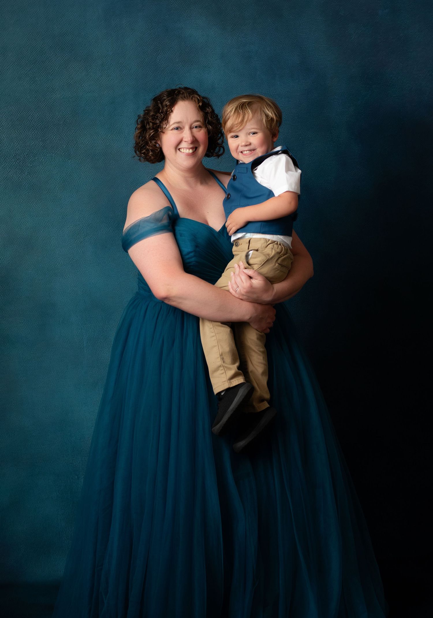 A vibrant teal ballgown dress with a full gathered skirt is shown against a warm autumn background.