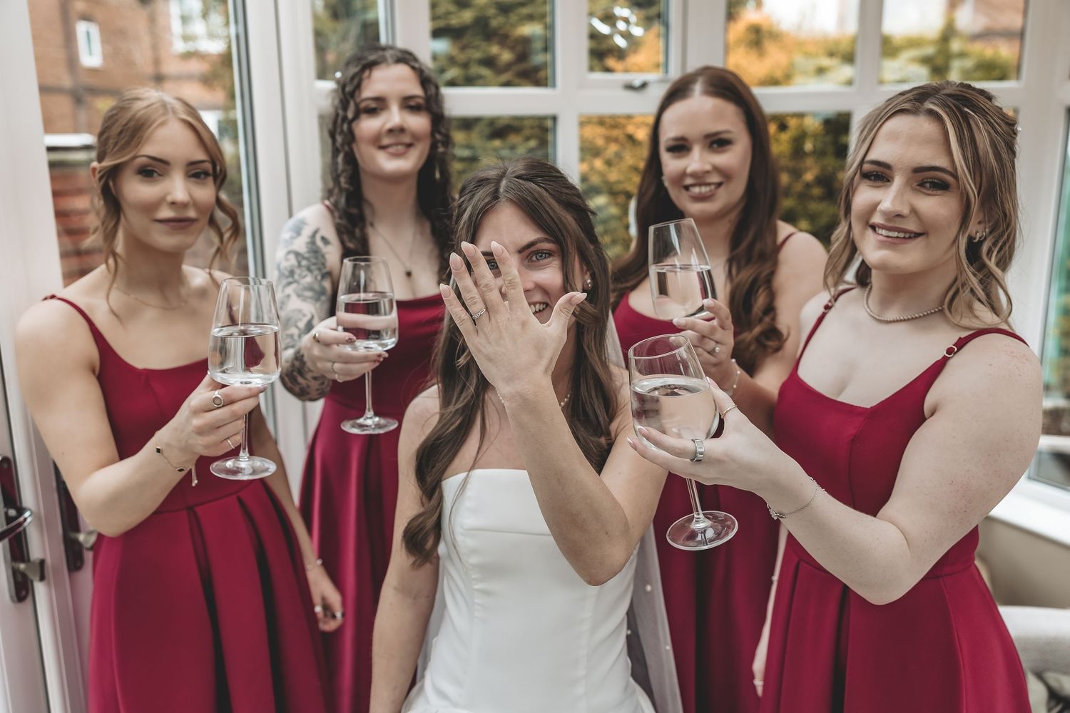 A posed moment of bride showing off her ring surrounded by her bridesmaids during bridal prep.