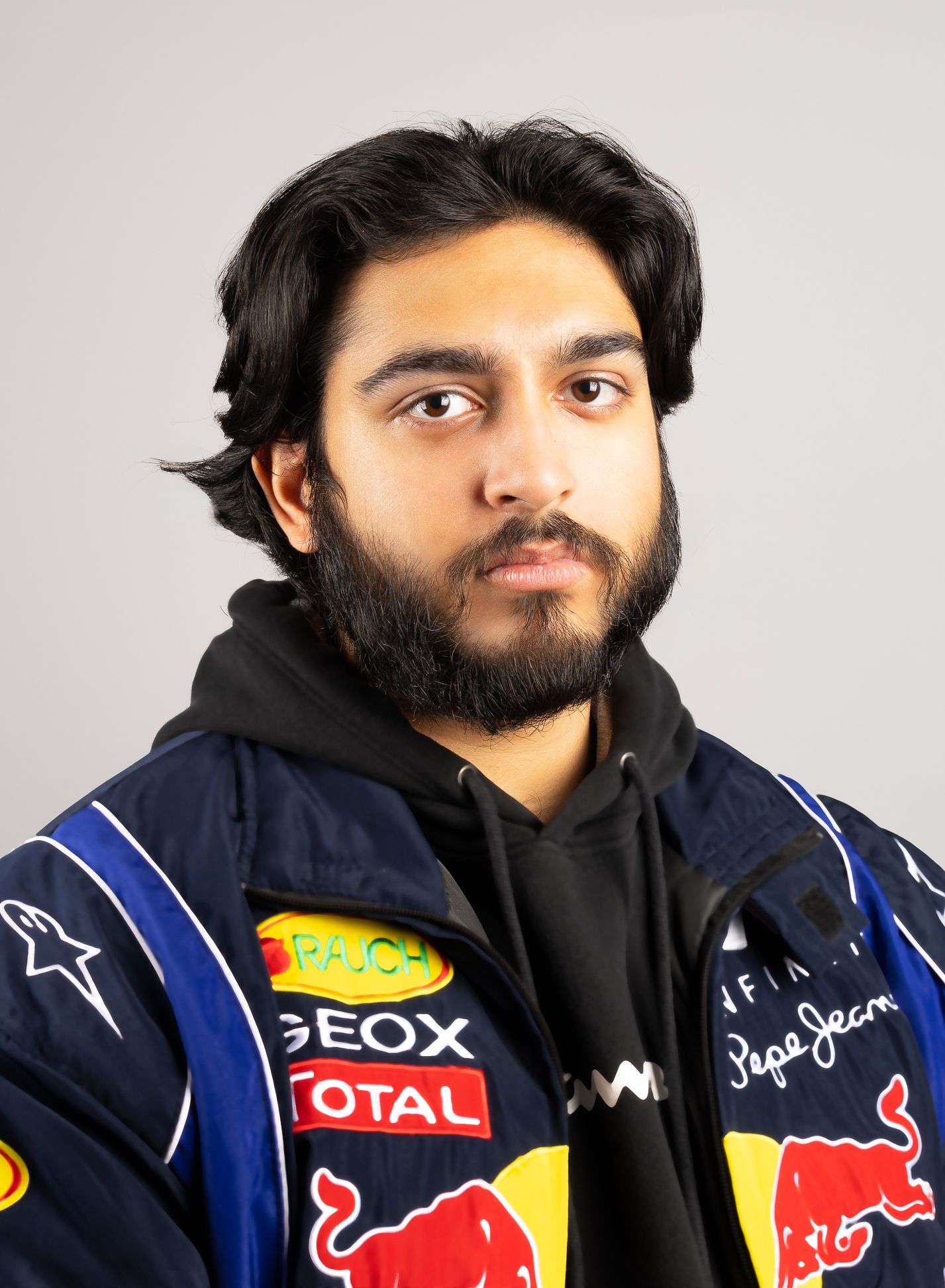 image of a man in a racing jacket and hoodie, with no smile, looking at the camera