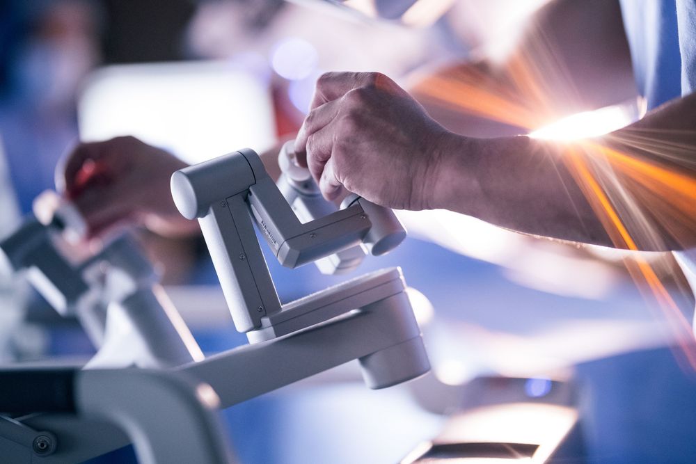 Close-up of hands adjusting a microscope in a bright laboratory setting with lens flare.