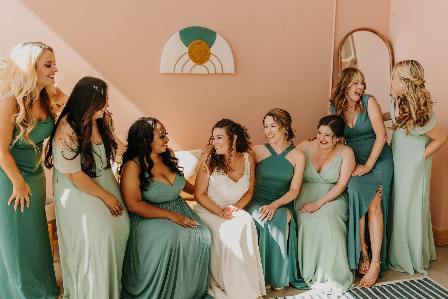 Bride in white gown laughing with bridesmaids in sage green dresses during wedding preparations at The Lane.
