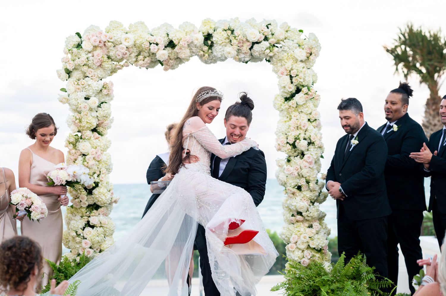 The groom celebrates by carrying his wife down the stairs as South Florida wedding photographers document the moment.