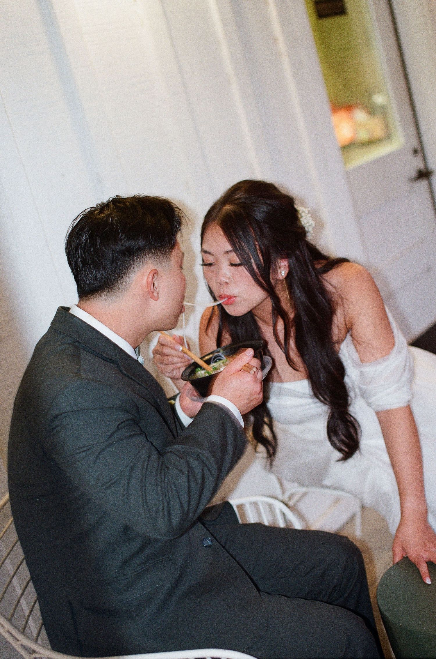 Unique film photo of the couple sharing late-night Pho soup during their Orange County wedding reception.