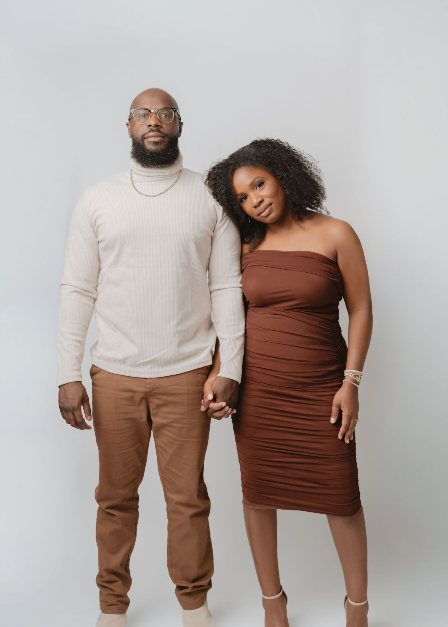 A couple in coordinating brown and beige outfits poses together in four similar studio shots against a white backdrop.