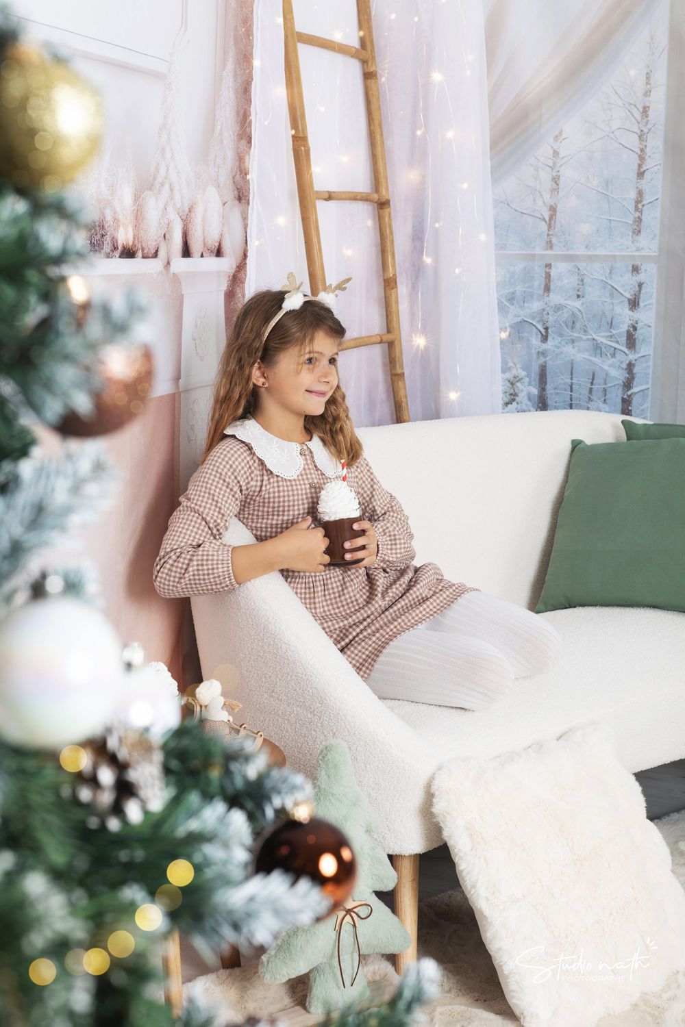 A cozy winter scene with a decorated Christmas tree, white sofa, and soft lighting by a snowy window backdrop.