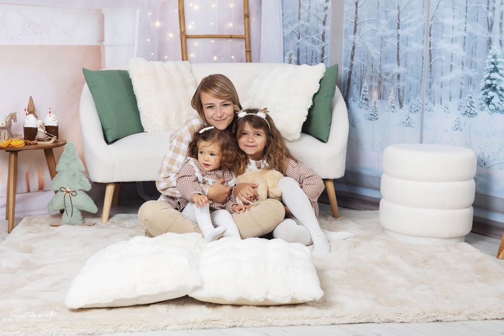 A cozy winter family scene with white fluffy pillows and a modern couch against a snowy backdrop.