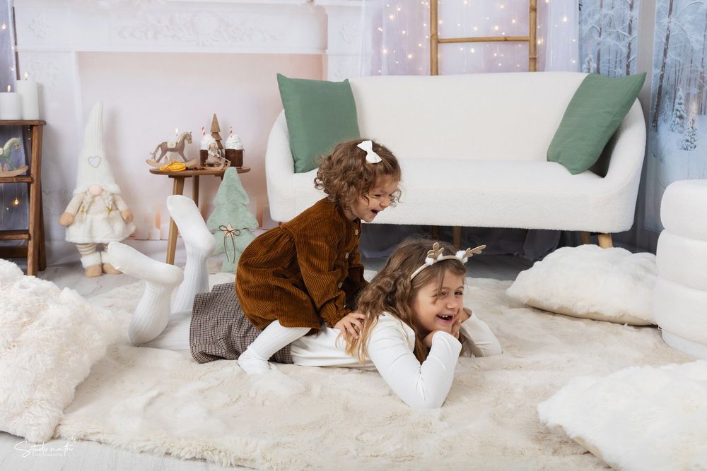 Child and chocolate-colored dog playing together on plush white carpet near living room couch.