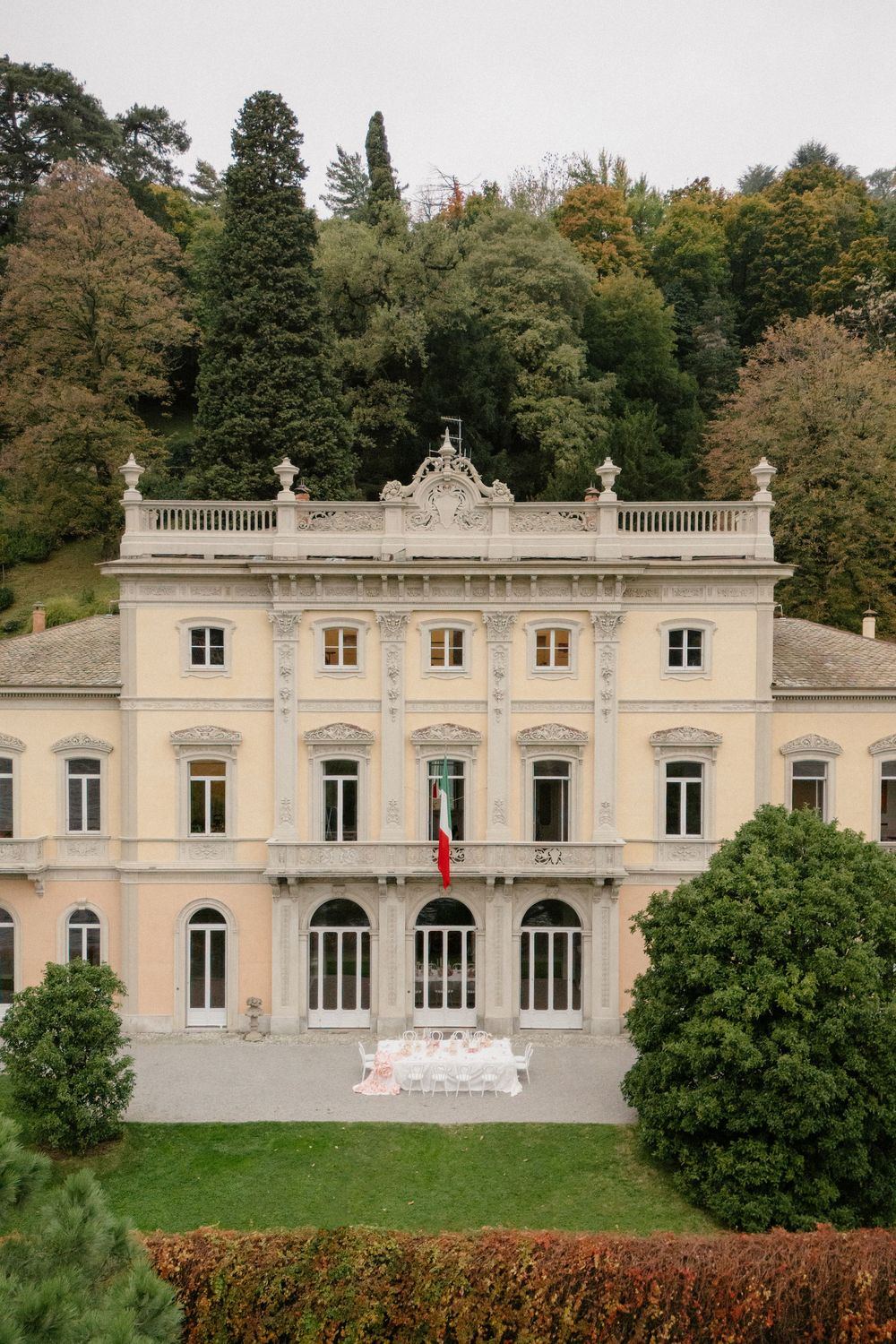 Panoramic view of a grand neoclassical white mansion with multiple windows and ornate architectural details.