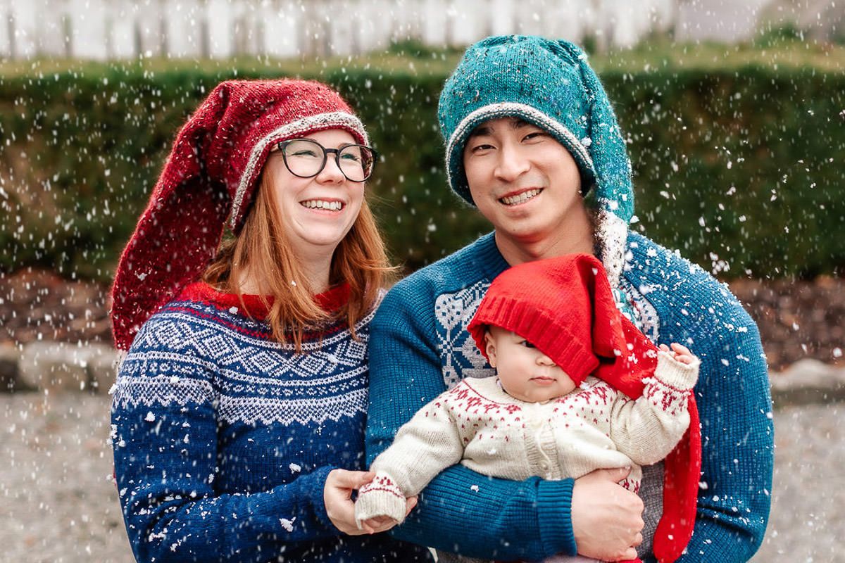 Mor, far og baby på 7 måneder på julekortfotografering på Ålgård, står i snø og smiler til kamera. Babyen har nisselua på snei.