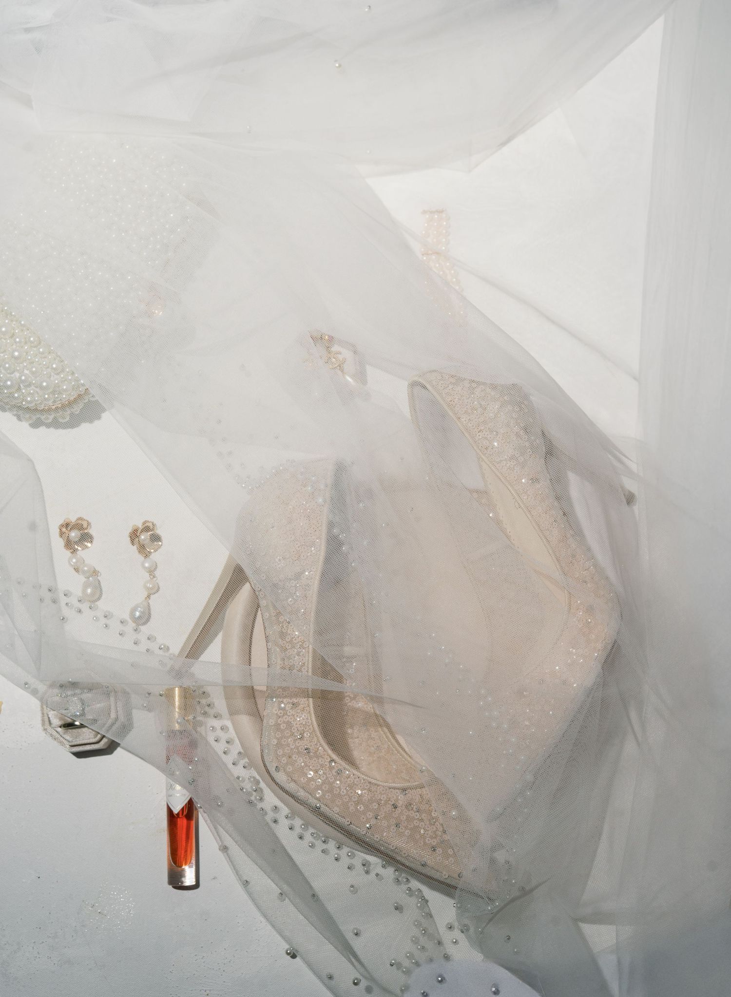 Ethereal white tulle and lace wedding gowns hanging in a row with delicate beaded details and flowing fabrics.