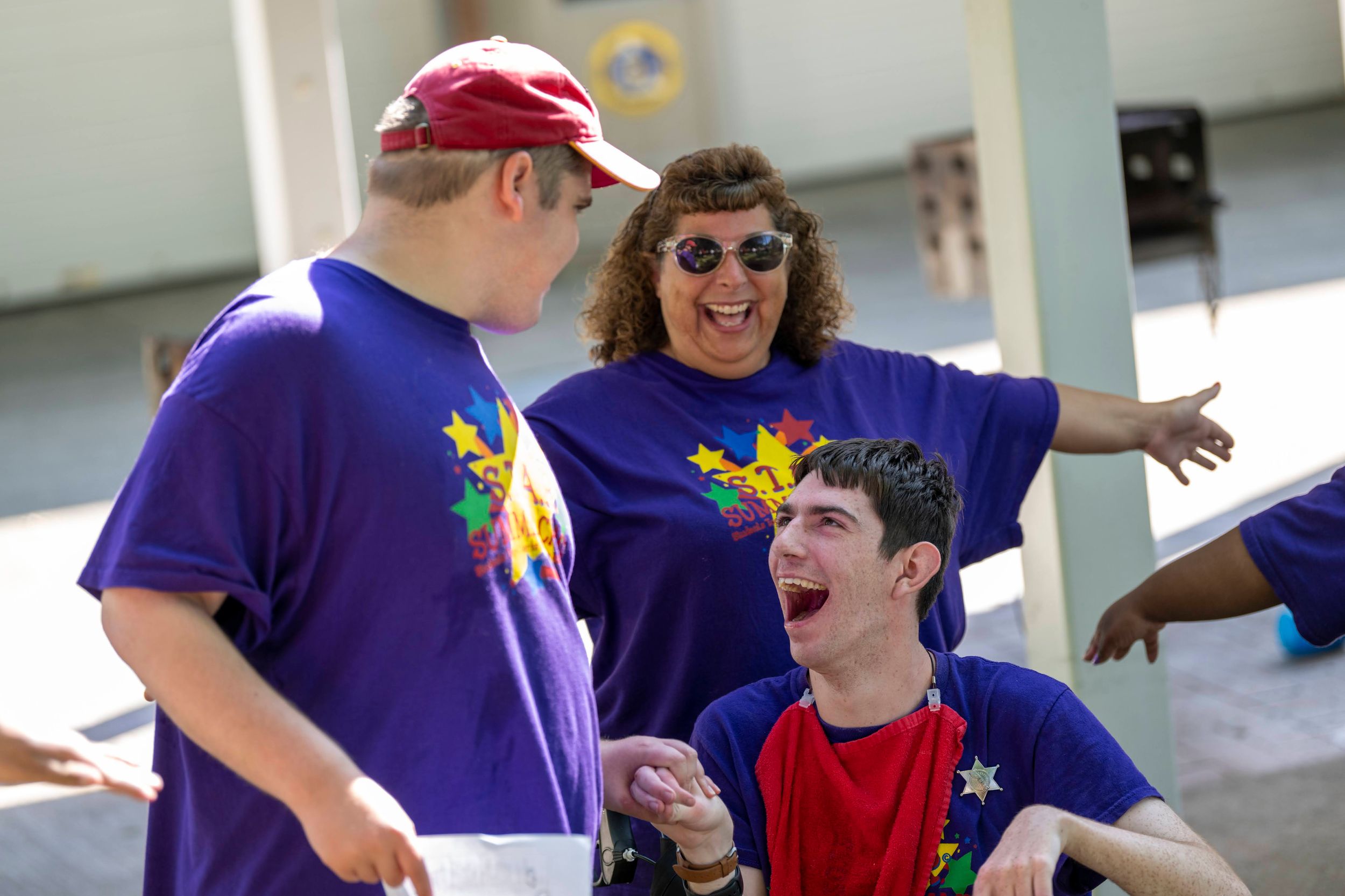 People in purple and red shirts interacting and having fun at an outdoor event.