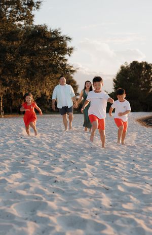 Family running and playing together on white sand dunes at sunset.