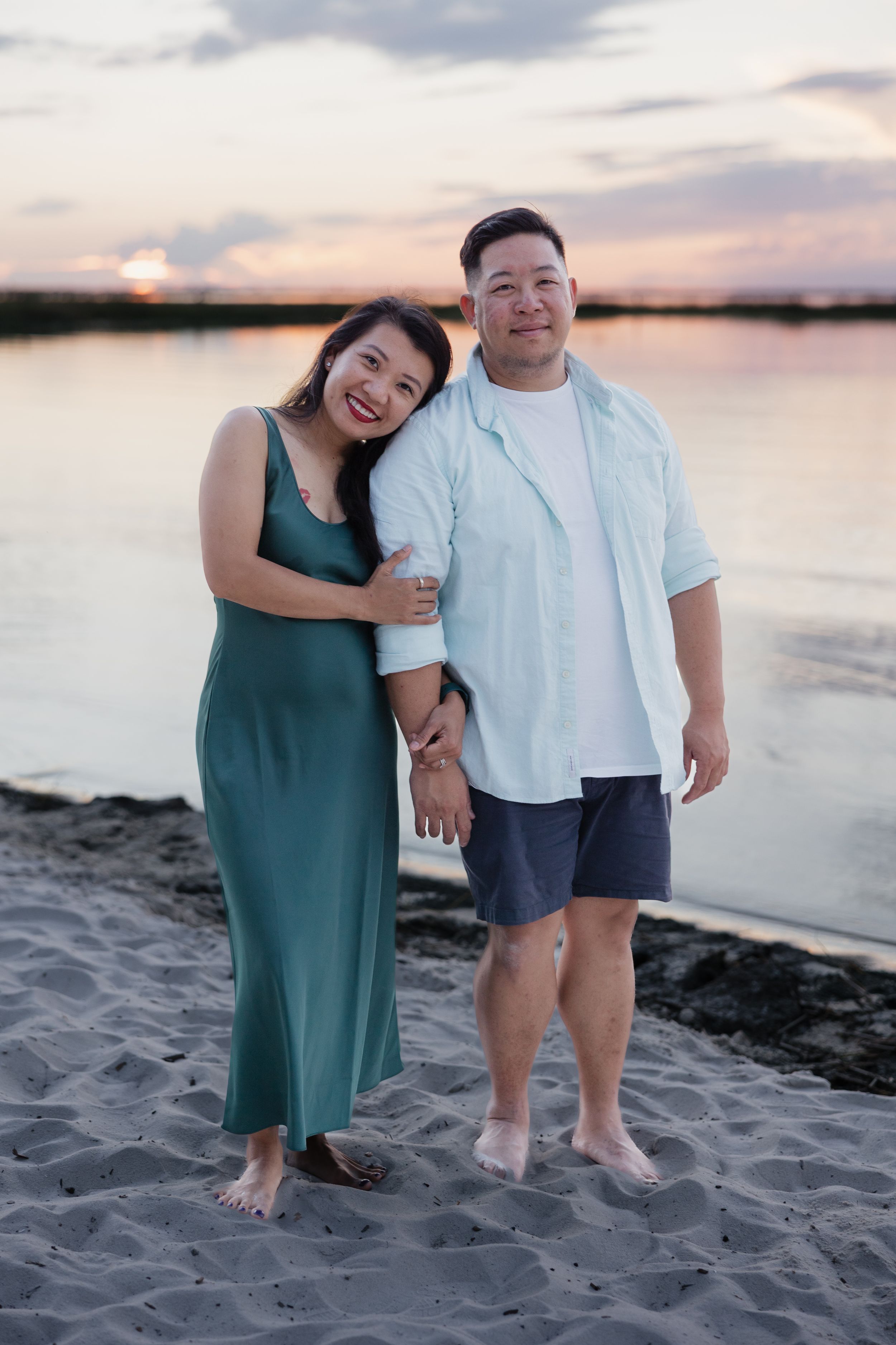 Family enjoying sunset moment together on sandy beach.