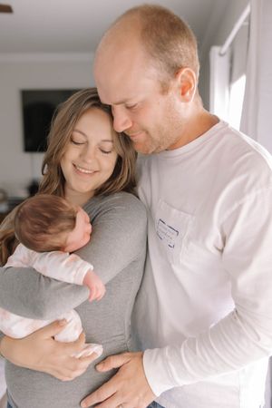 Intimate family moment with couple embracing and smiling in white and grey clothing.