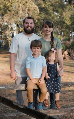 Family sitting together on wooden log during outdoor photo session.
