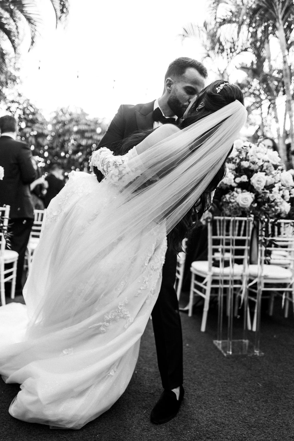 A romantic wedding couple dips and dances together during their outdoor garden reception celebration.