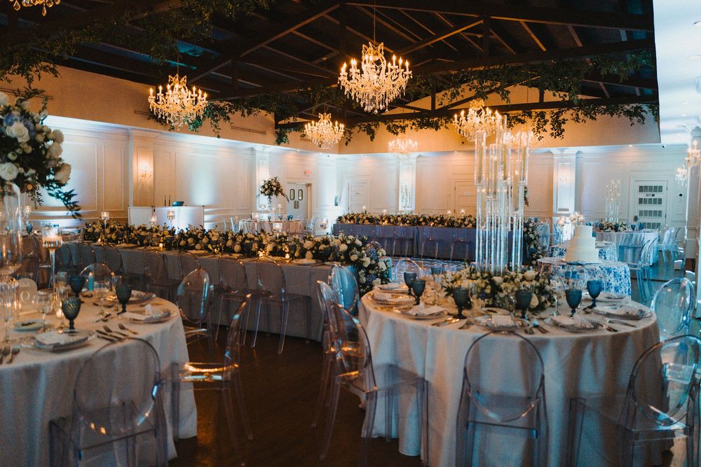 Elegant wedding reception venue with crystal chandeliers, white linens, and round tables set for a formal celebration.