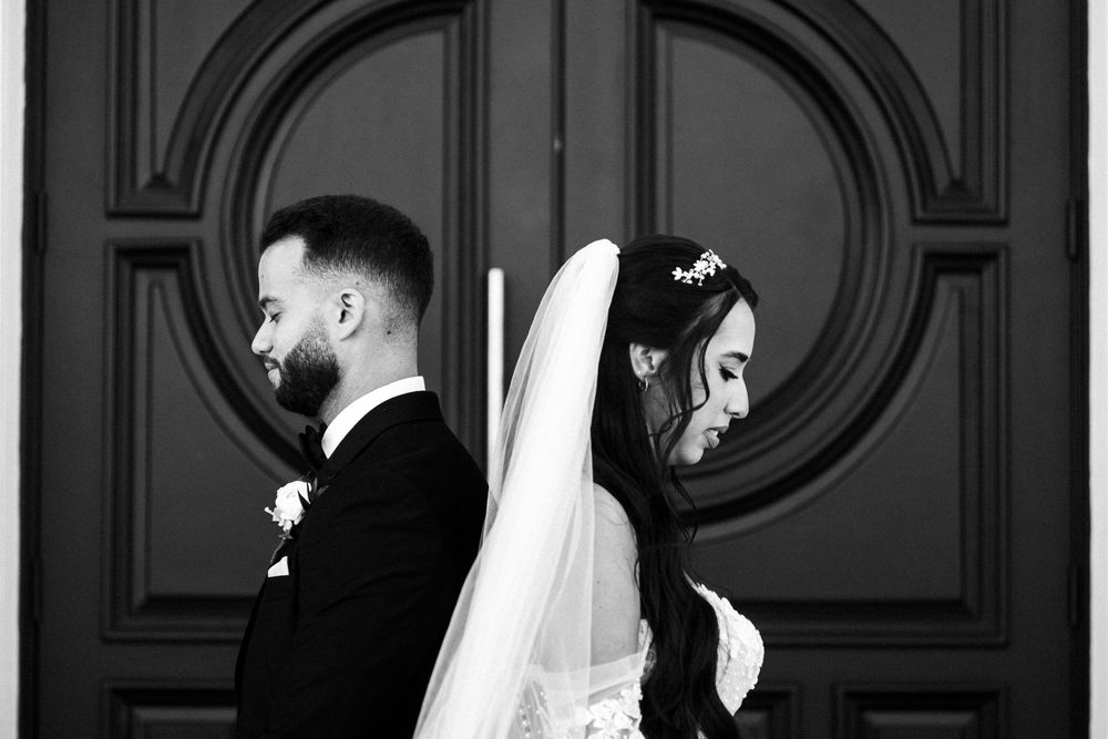 A wedding couple shares a tender kiss in a black and white photograph.
