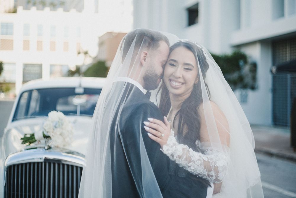 A bride and groom share intimate moments together during their wedding photoshoot on a city street.