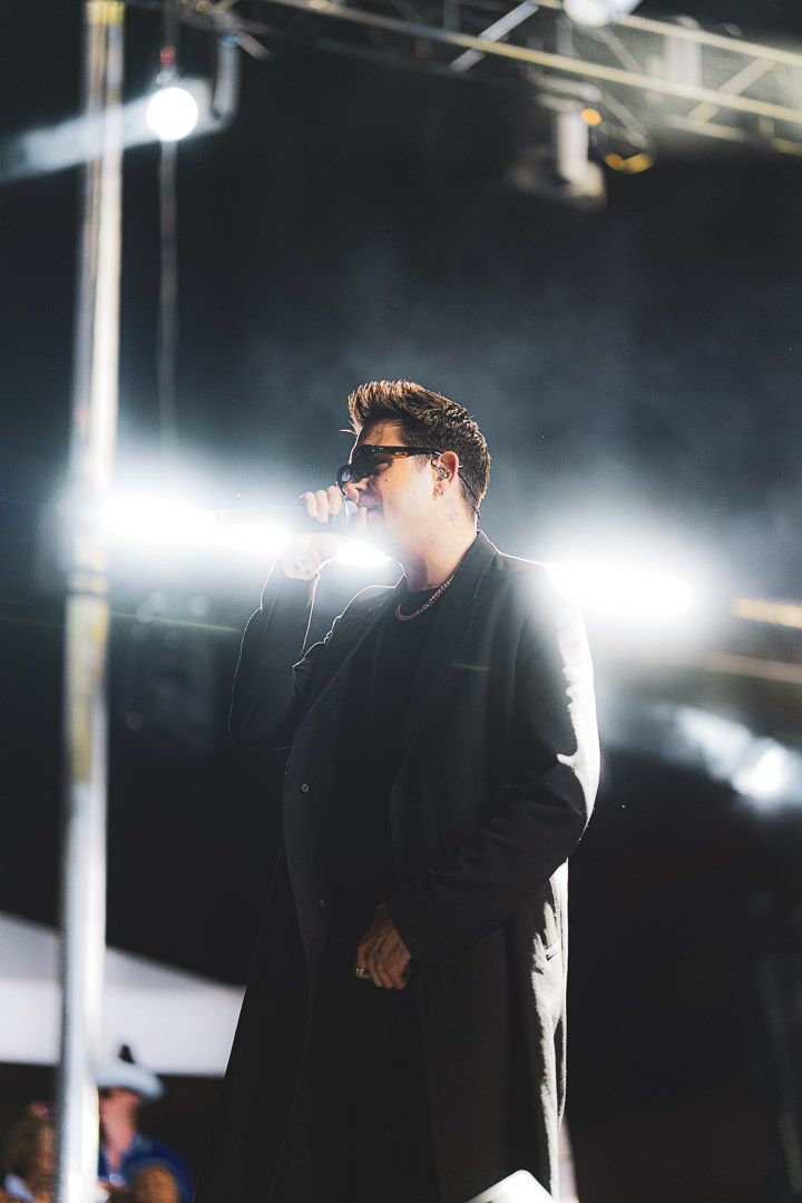 Performer in black clothing illuminated by bright stage lights during live show.