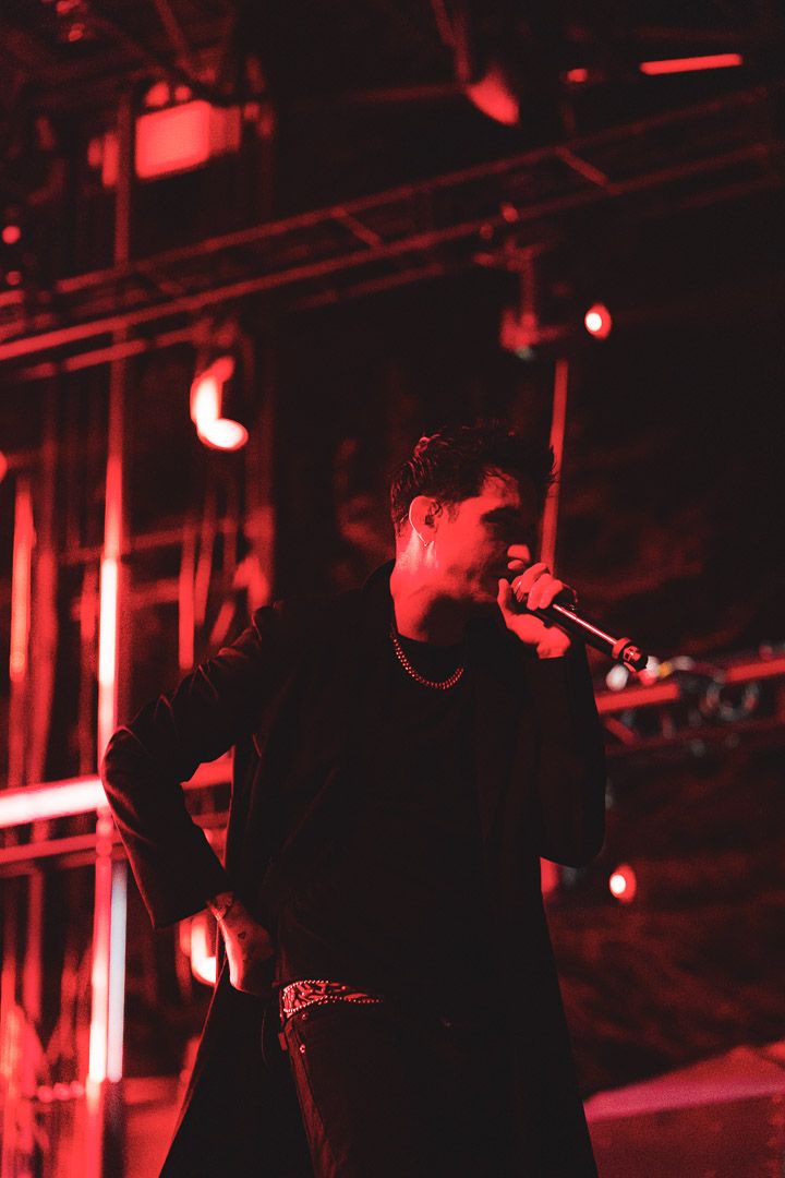 Concert performer silhouetted in dramatic red lighting on stage during a live performance.