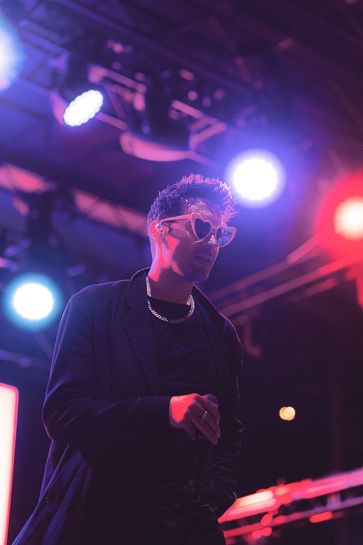 Dramatic concert performance captured under blue and red stage lights creating moody atmosphere.