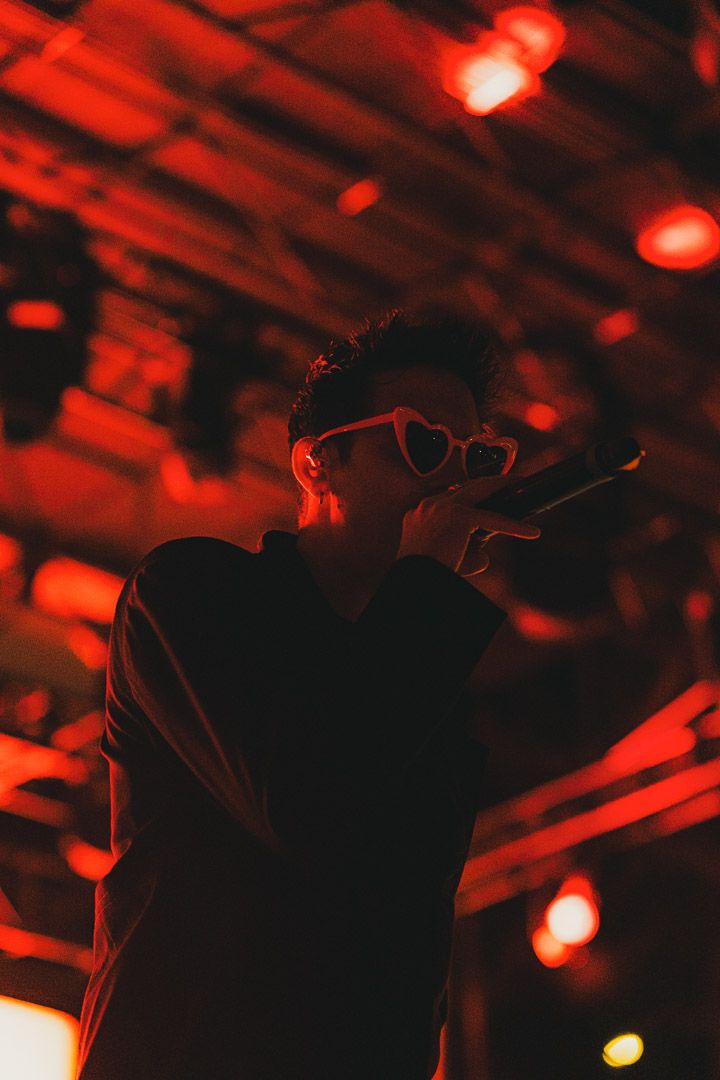 Silhouetted performer on stage illuminated by dramatic red lighting and spotlights during a concert performance.