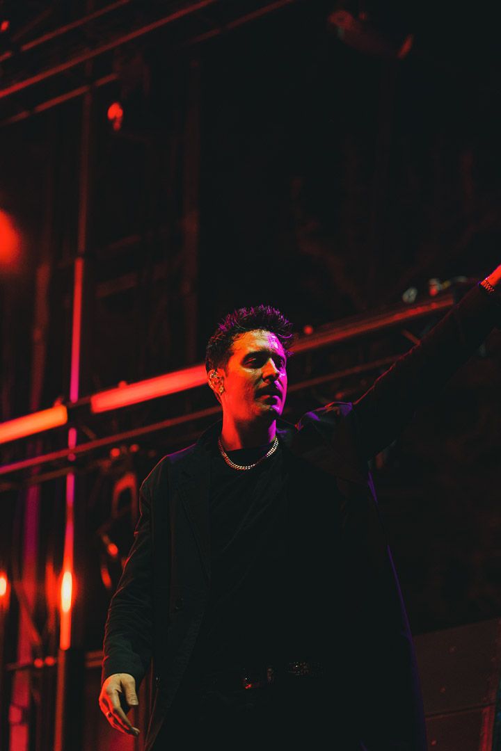 Dark concert scene with performer highlighted by intense red stage lighting.