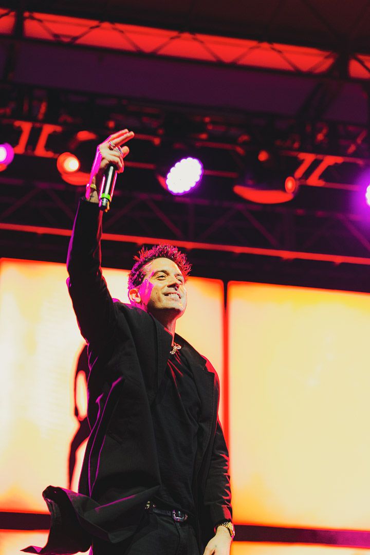 A dramatic concert scene with a performer silhouetted against vibrant red and yellow stage lighting.